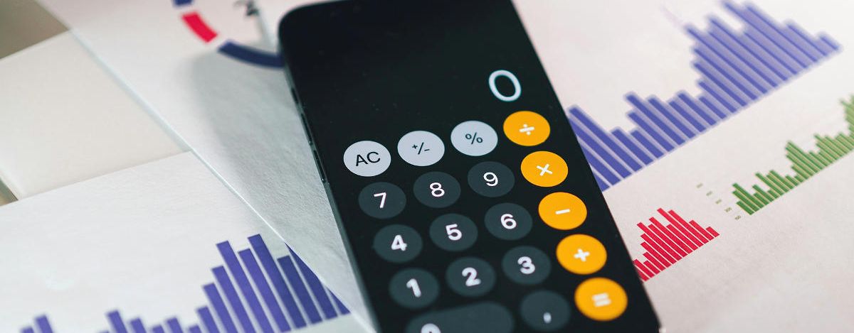 Smartphone-Taschenrechner liegt auf ausgedruckten Statistiken